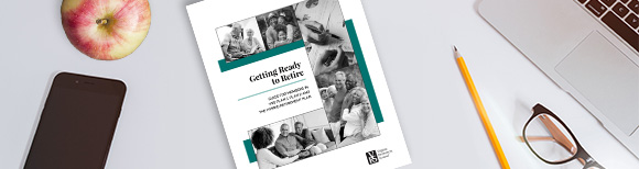 منظر لمكتب من الأعلى مع هاتف أبل وقلم رصاص وزوج من النظارات وجهاز كمبيوتر محمول بالإضافة إلى نسخة من دليل الاستعداد للتقاعد من VRS.