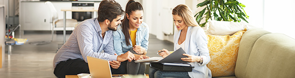 رجل وامرأة يجلسان على الأريكة معًا ينظران إلى شيء ما على شاشة كمبيوتر محمول وآخر قريب