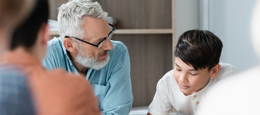 Adulto y niño sentados juntos en una mesa revisando artículos.