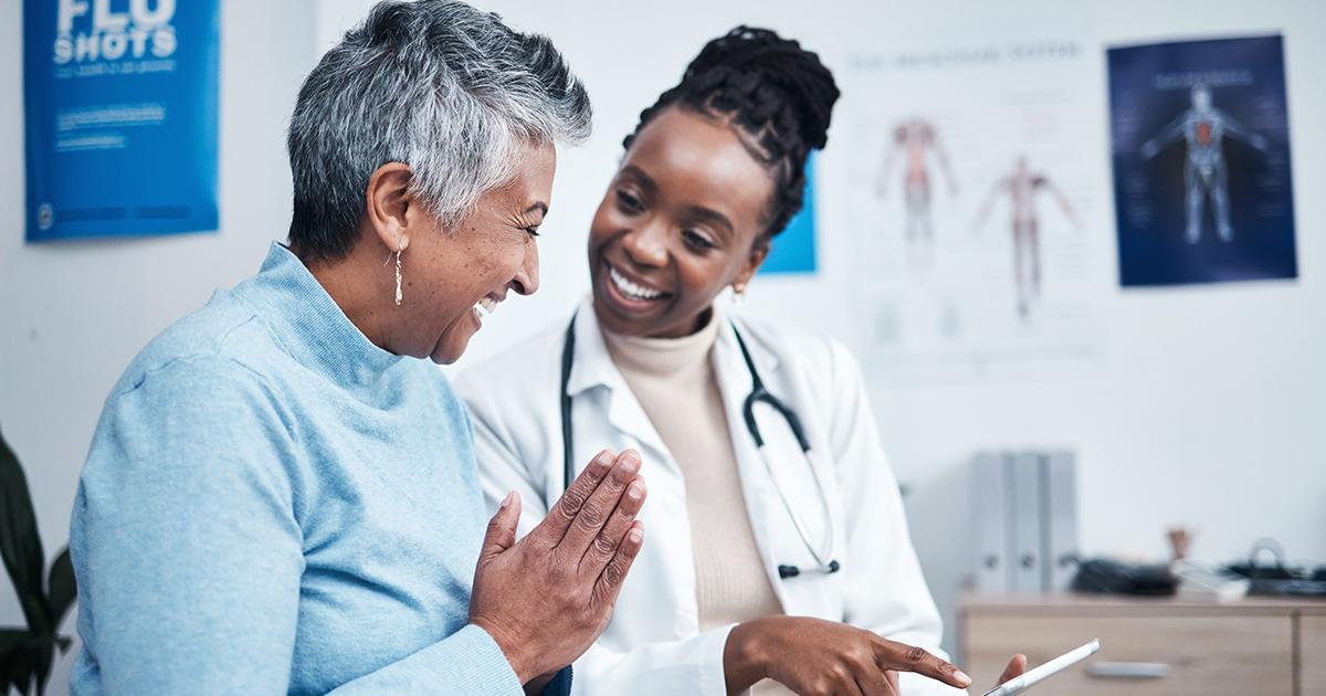 Décoratif. Une femme d'âge mûr et son médecin sourient en discutant de ce qui est écrit sur le bloc-notes du médecin.