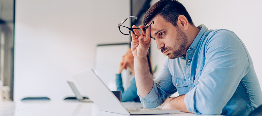 Une personne assise à un bureau, la main sur le front