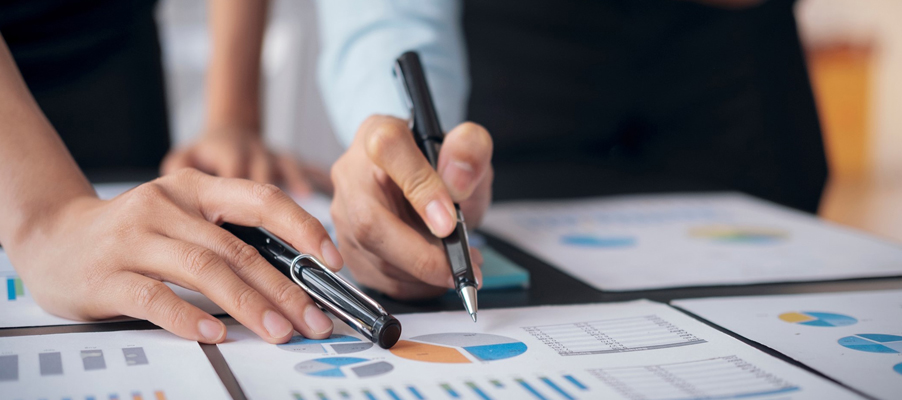 Une personne tenant un stylo et pointant du doigt un graphique