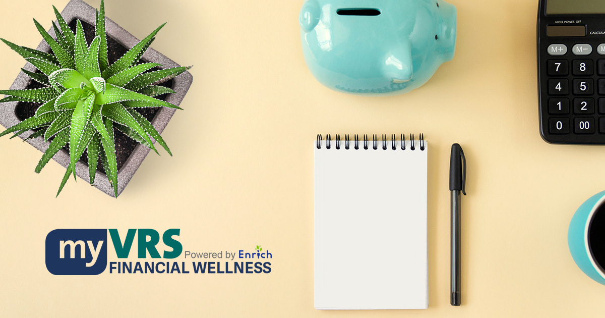 장식. 화분에 담긴 다육식물, my VRS Financial Wellness 로고, 도자기 저금통, 노트, 필기구, 계산기, 블랙 커피가 담긴 커피잔의 일부를 위에서 바라본 모습입니다.