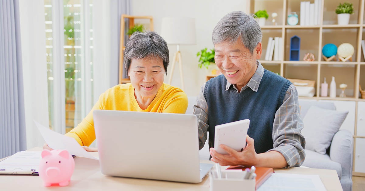 장식용. 한 노부부가 노트북으로 가계부를 확인하며 미소를 짓고 있다.