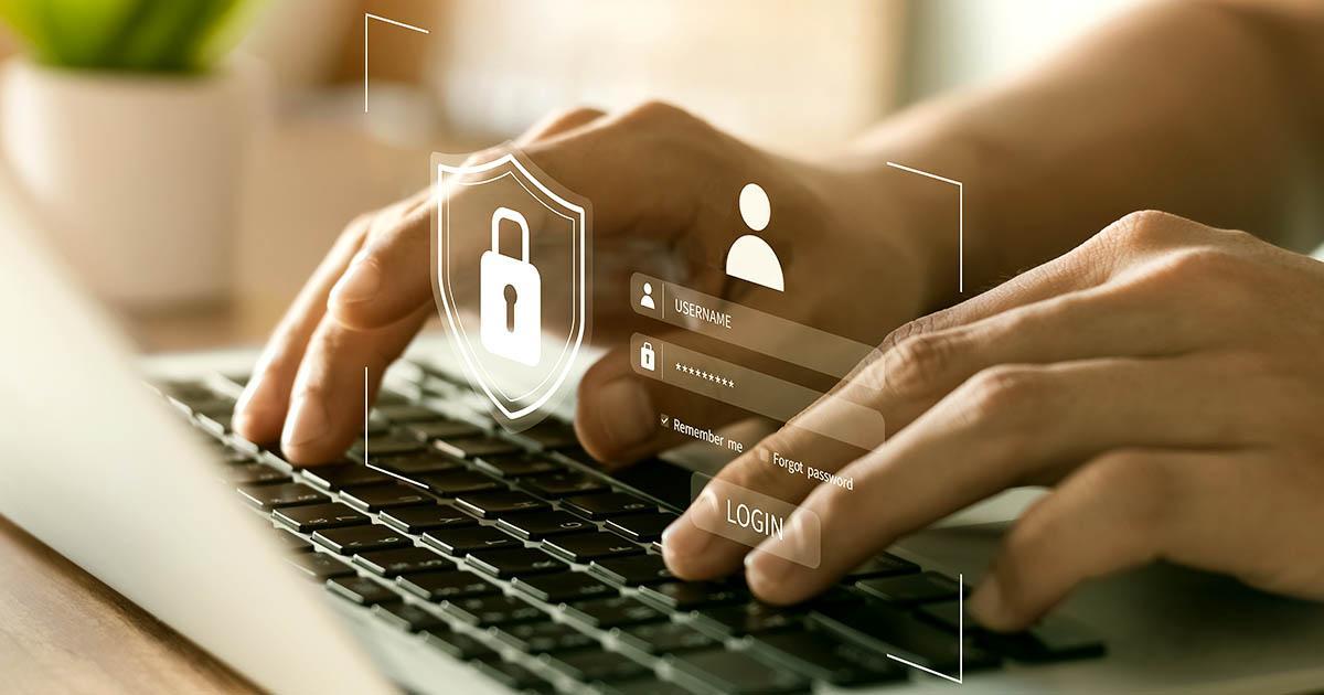 Decorative. Hands typing on a laptop computer with username and password fields, and a padlock graphic superimposed over them.