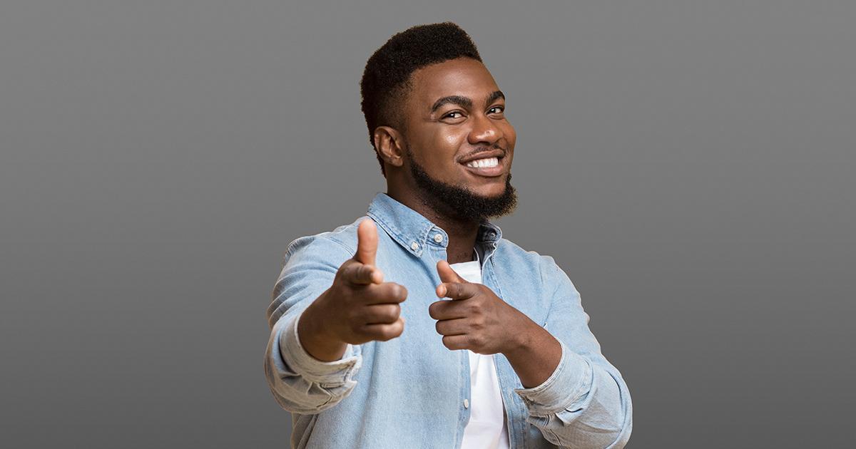 Decorative. A smiling man points the index fingers of both hands toward the viewer.