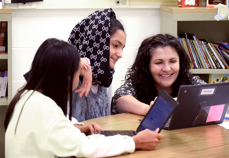 Fabiana Parker instructing two students at a table in her classroom.