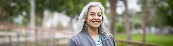 A female university administrator smiles as she walks across campus to her office.