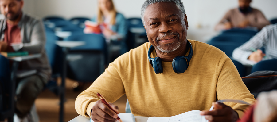 [Pérs~óñ sé~átéd~ íñ á c~láss~róóm~ hóld~íñg p~ápér~s áñd~ wrít~íñg, w~íth ó~thér~s íñ t~hé bá~ckgr~óúñd~.]